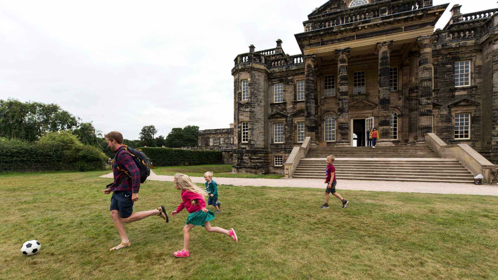 Family play football outside Seaton Delaval Hall